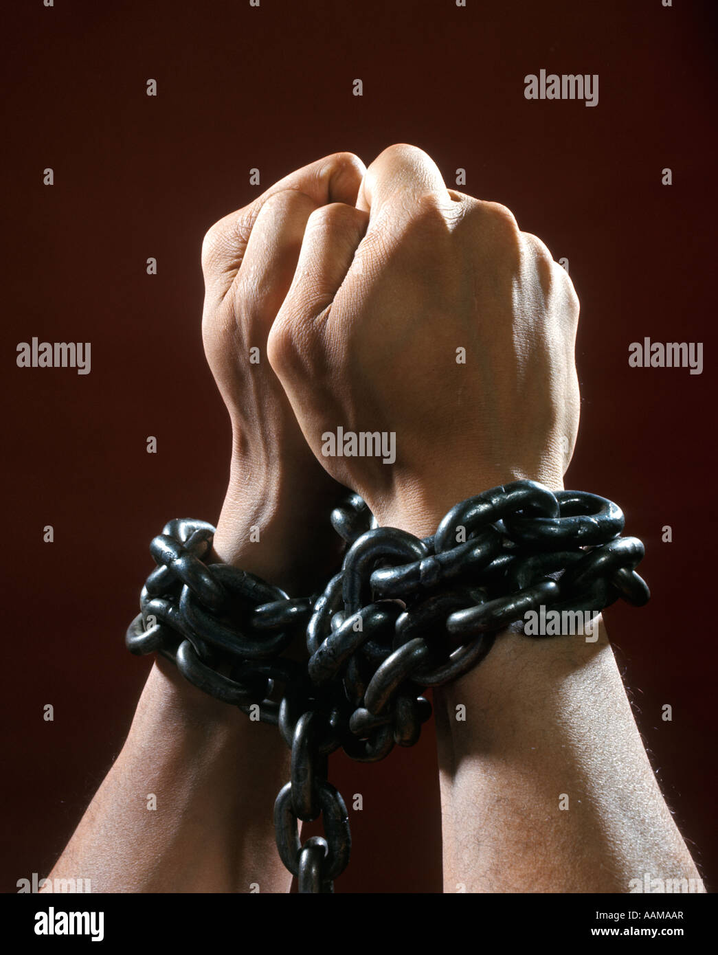 MANS HANDS FISTS TIED WITH CHAIN CHAINS PRISONER CHAINED CAPTIVE CRIMINAL CAUGHT PRISON CAPTURED Stock Photo