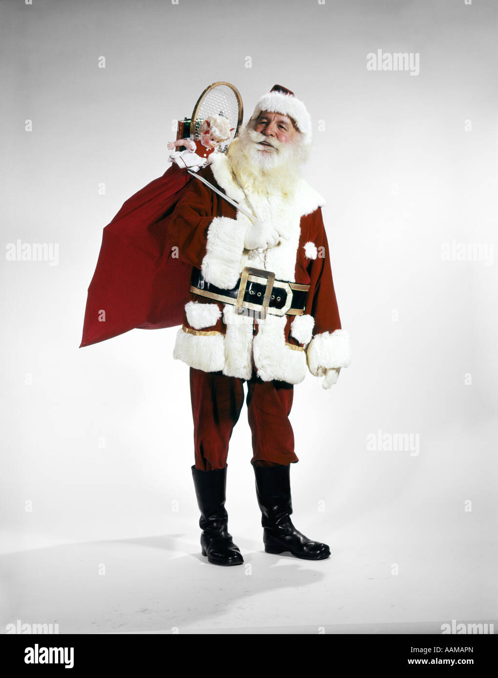 1960s FULL LENGTH PORTRAIT OF SANTA CLAUS WITH STUFFED TOY SACK ON HIS BACK STUDIO Stock Photo