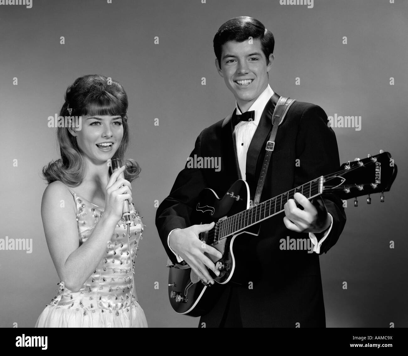 1960s TEENAGE ENTERTAINMENT DUO MAN PLAYING GUITAR AND WOMAN SINGING HOLDING MICROPHONE Stock Photo