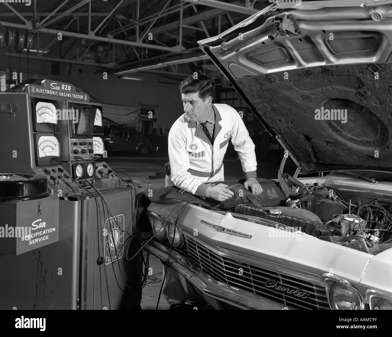 1960s AUTO AUTOMOBILE MECHANIC TESTING ENGINE ELECTRONICS UNDER HOOD CAR TUNE UP CHECK REPAIR Stock Photo