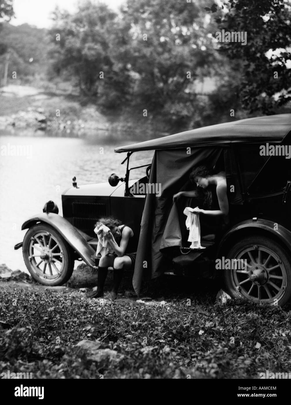 1920s TWO WOMEN CAMPING LAKESIDE IN AUTOMOBILE DRYING OFF CHANGING CLOTHES AFTER SWIMMING Stock Photo