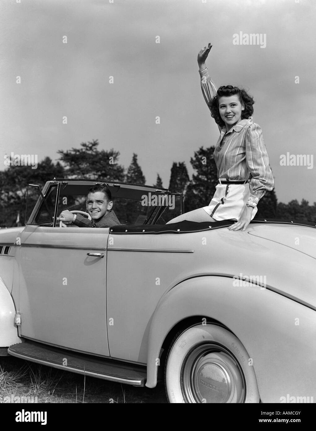 1940s COUPLE CAR DRIVING CONVERTIBLE SMILE WAVING Stock Photo
