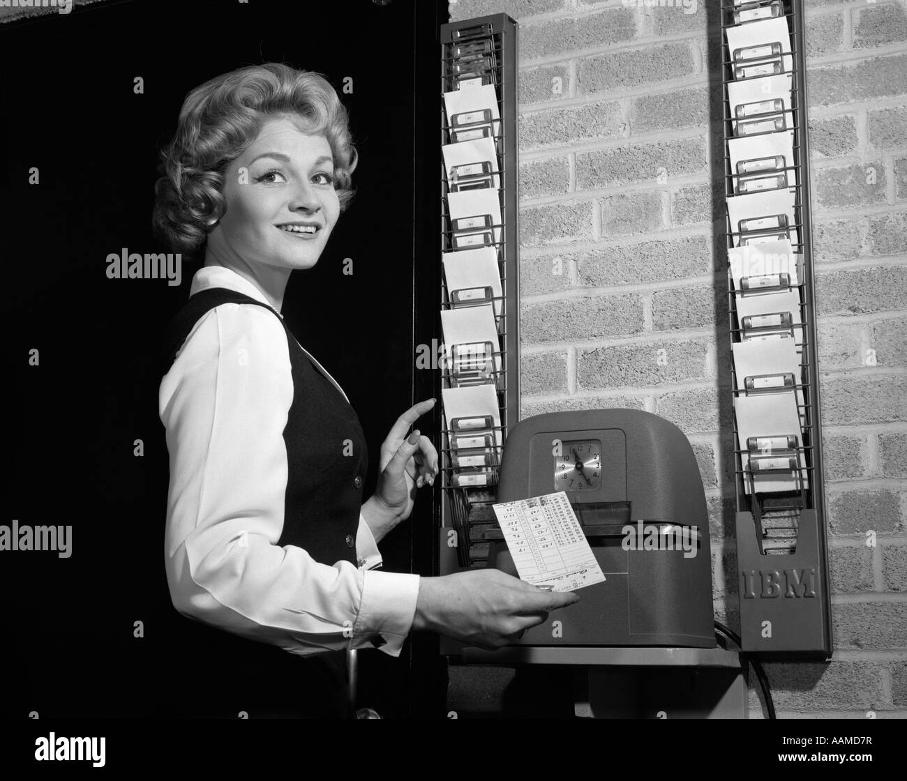 1950s WOMAN IN OFFICE WITH TIMECARD AND TIMECARD CLOCK Stock Photo