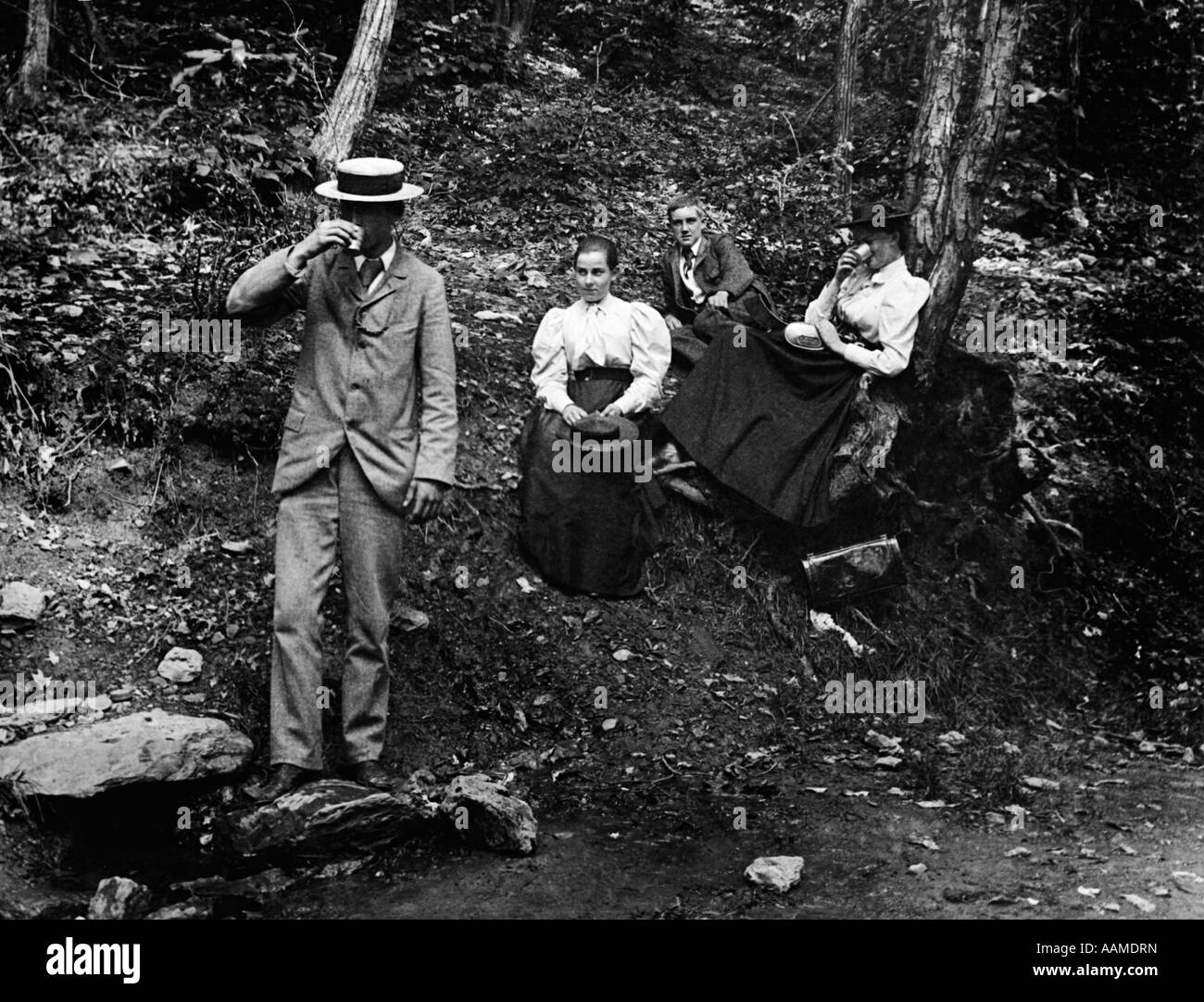 1890s 1900s GROUP OF TWO MEN & TWO WOMEN IN WOODS ONE MAN & ONE WOMAN DRINKING Stock Photo