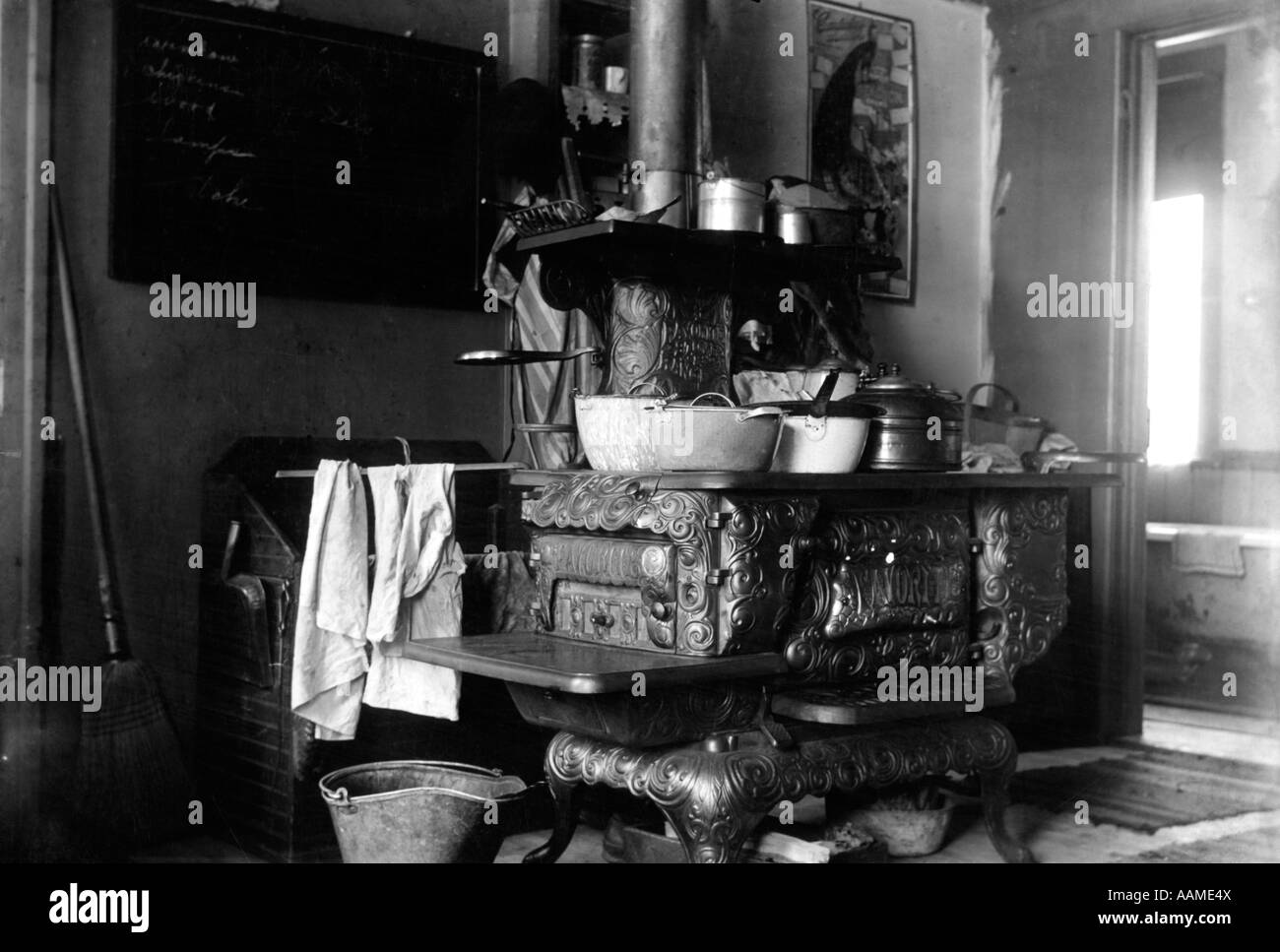 1890s 1900s TURN OF CENTURY CAST IRON WOOD BURNING COOK STOVE WITH POTS AND PANS IN KITCHEN Stock Photo