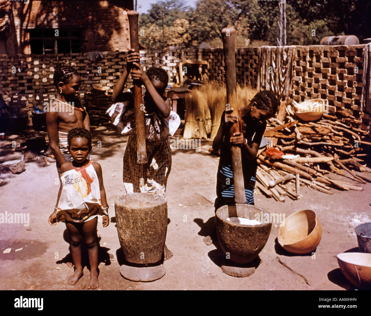 GRINDING MILLET MORTAR PESTLE PRIMITIVE FARMING METHODS THIRD WORLD MALI AFRICA Stock Photo