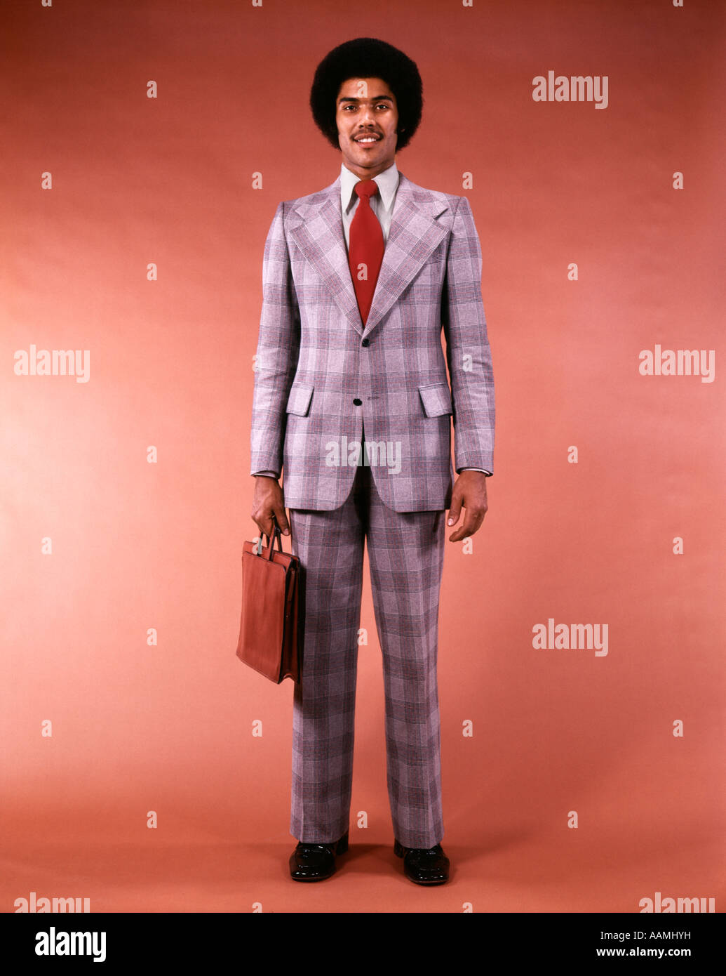 1970s ARICAN-AMERICAN ETHNIC BUSINESSMAN PORTRAIT FULL FIGURE HOLD BRIEFCASE IN GLEN PLAID SUIT MAN FASHION AFRO HAIR Stock Photo