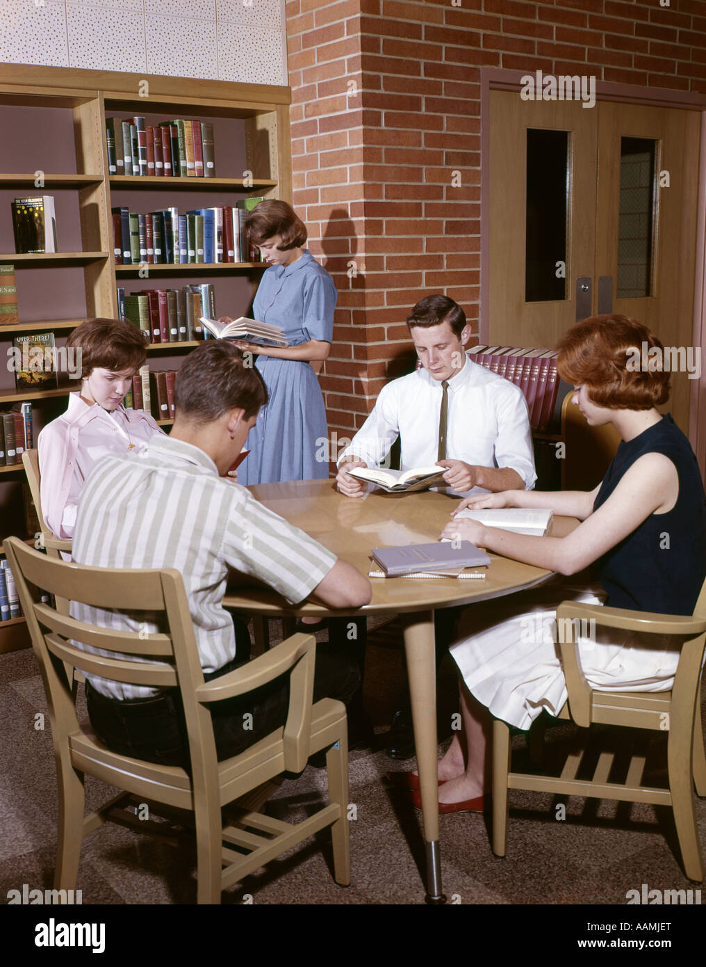 1960s COLLEGE STUDENTS STUDYING IN LIBRARY NOSTALGIA BOY GIRL MAN WOMAN ADOLESCENT Stock Photo