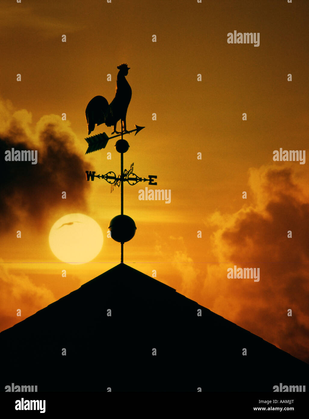 ROOSTER WEATHER VANE SILHOUETTED AGAINST SUNRISE SUNSET Stock Photo