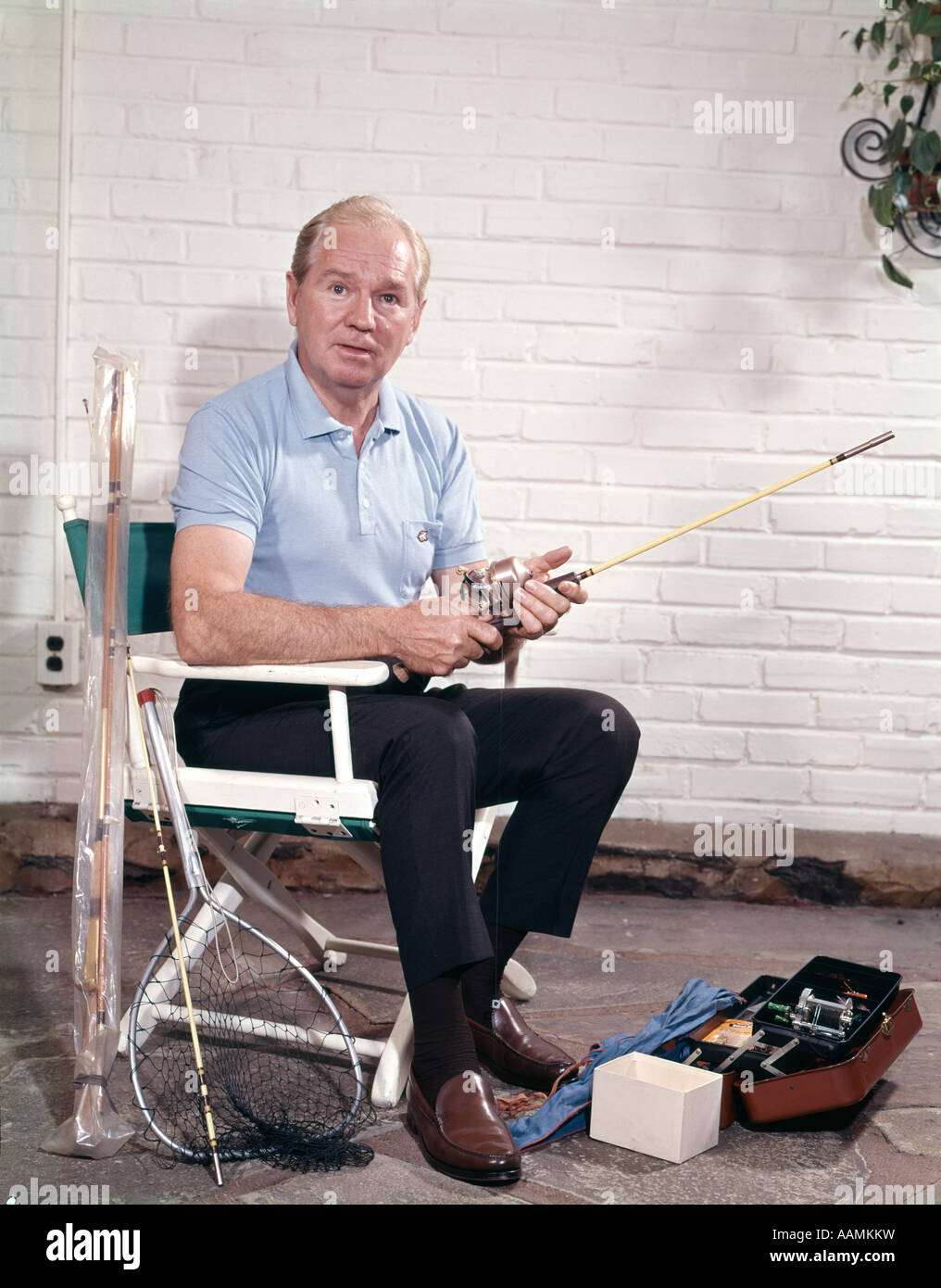 MAN SITTING IN CHAIR HOLDING FISHING ROD WITH TACKLE BOX AND NET Stock Photo Alamy