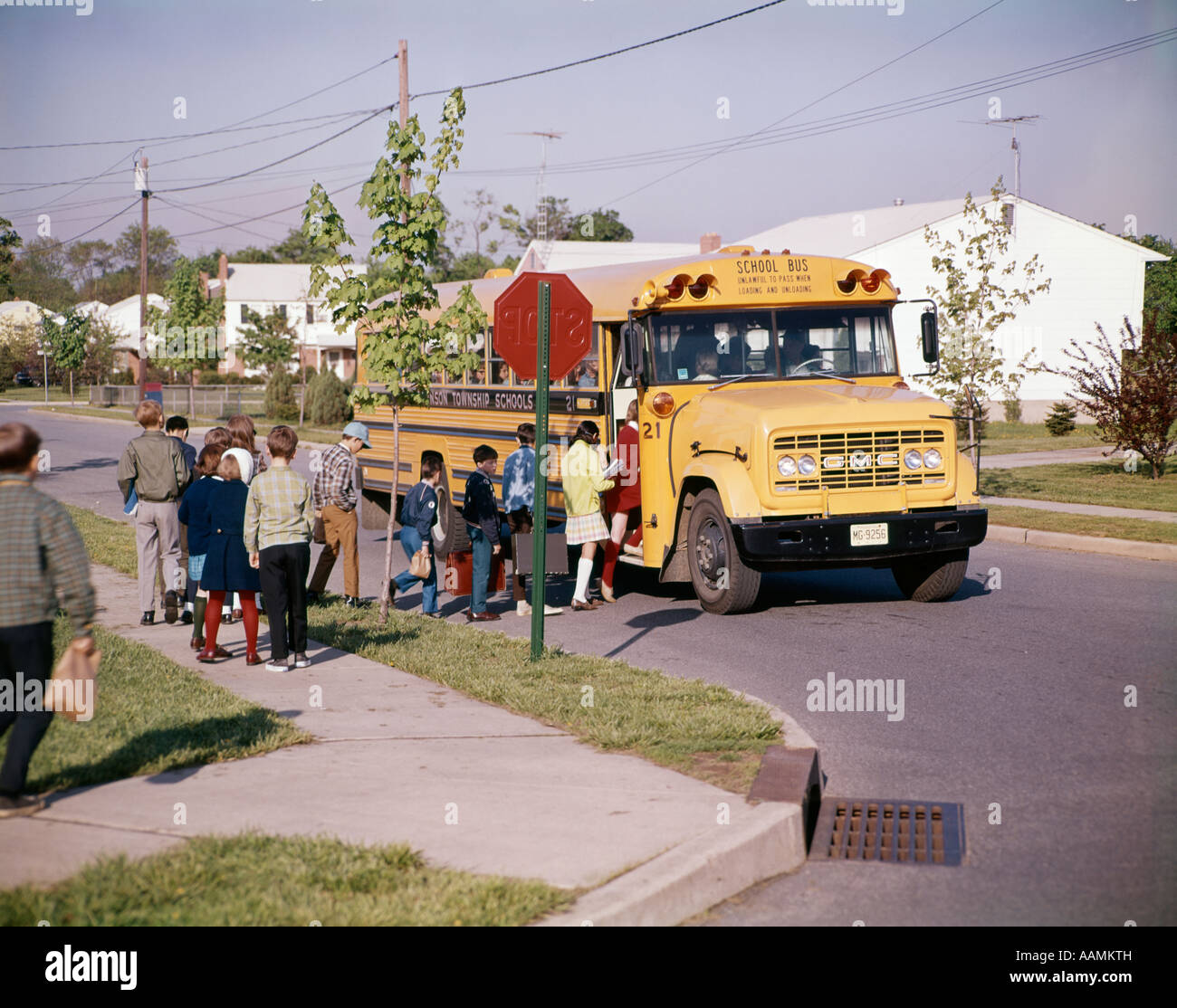1960s CHILDREN IN LINE BOARDING SCHOOL BUS CARRYING BOOKS BOY GIRL MANY