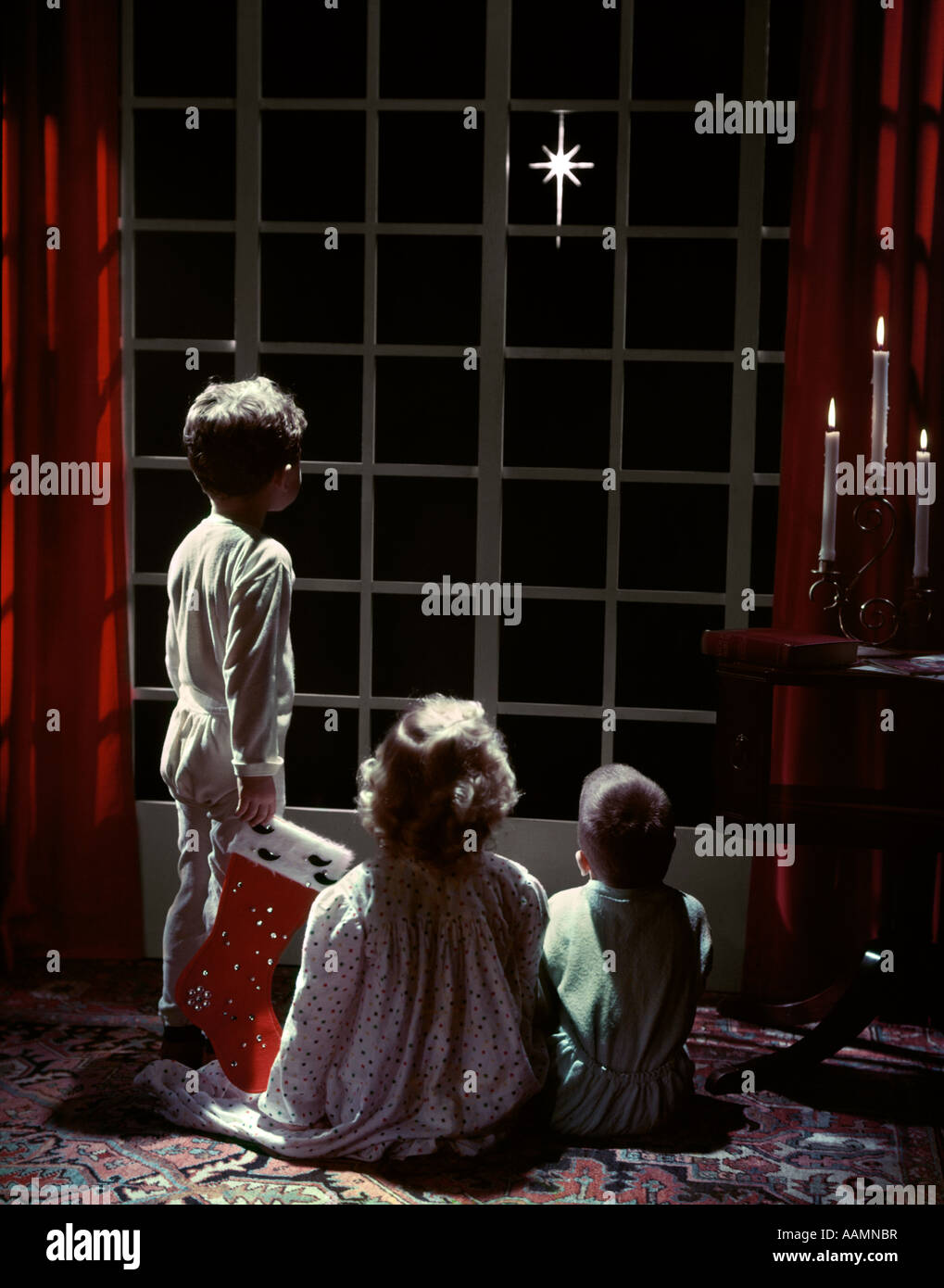 1950s 3 children 2 boys 1 girl pajamas look out french doors to star bethlehem christmas eve boy holds stocking studio - Children Christmas Pictures 2 1950s 3 children 2 boys 1 girl pajamas look out french doors to star bethlehem christmas eve boy holds stocking studio - Children Christmas Pictures 2