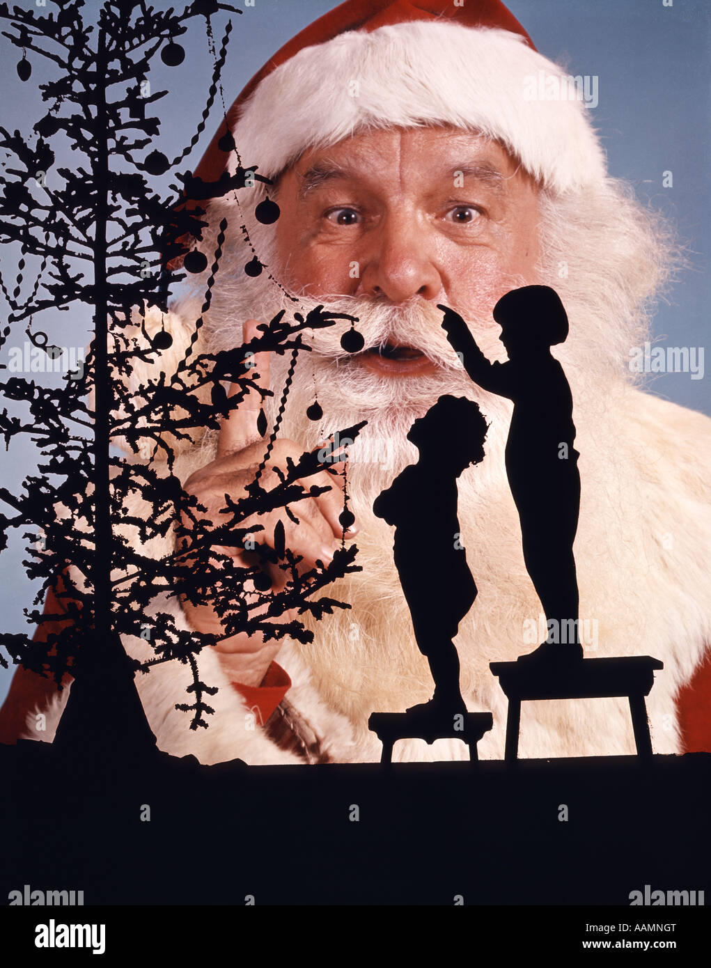 ANONYMOUS SILHOUETTED LITTLE BOY AND GIRL LOOKING UP AT CHRISTMAS TREE FACE OF SANTA CLAUS IN BACKGROUND LOOKING AT CAMERA Stock Photo