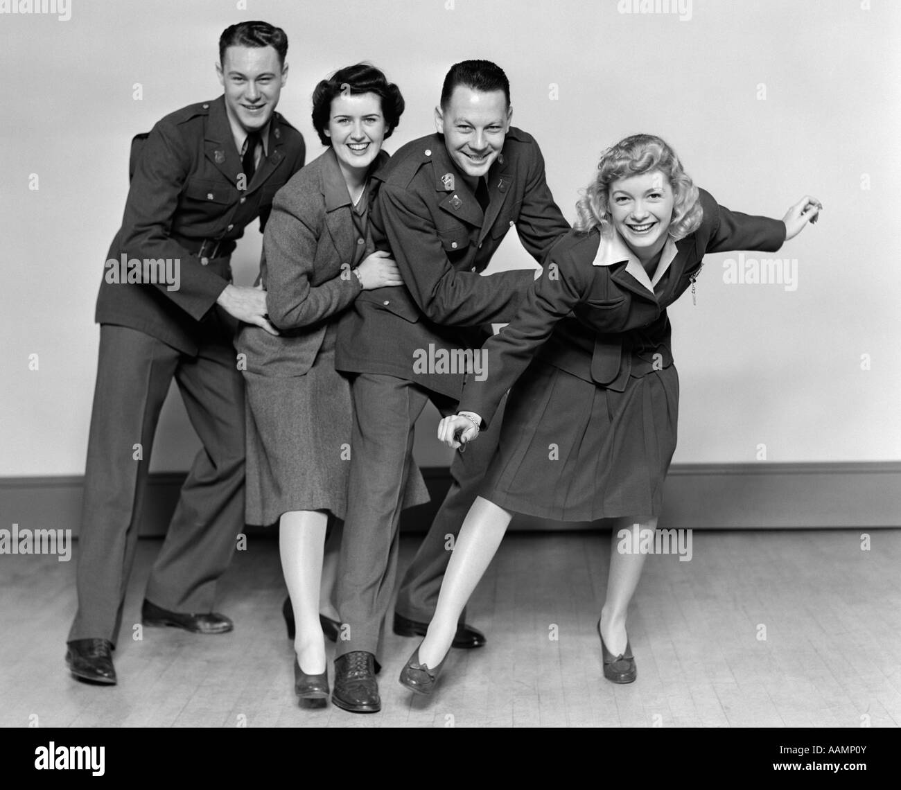 1940s CONGA LINE TWO MEN SOLDIERS AND TWO WOMEN DANCING SMILING LOOKING AT CAMERA Stock Photo