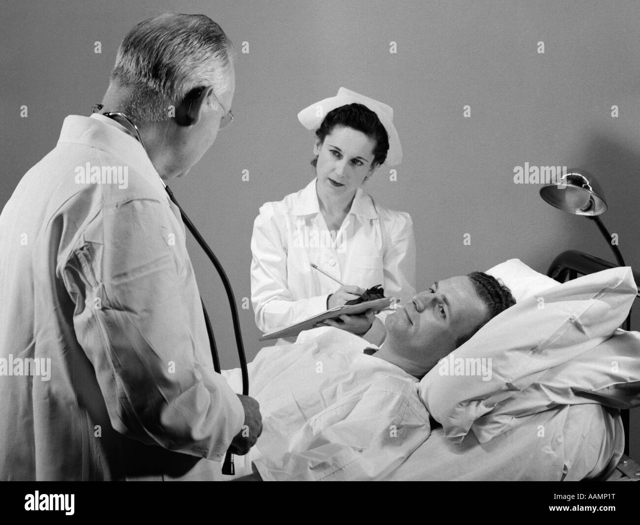 1950s DOCTOR NURSE PATIENT BED HOSPITAL SICK ILLNESS Stock Photo