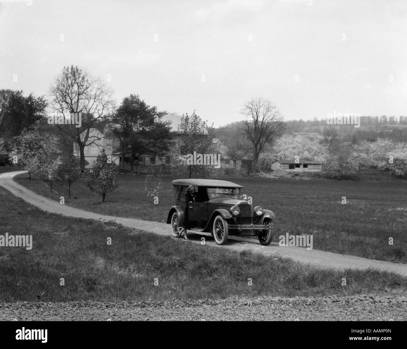 1930s 1940s PACKARD ON DIRT ROAD WITH WOMAN STANDING OUTSIDE PASSENGER SIDE Stock Photo