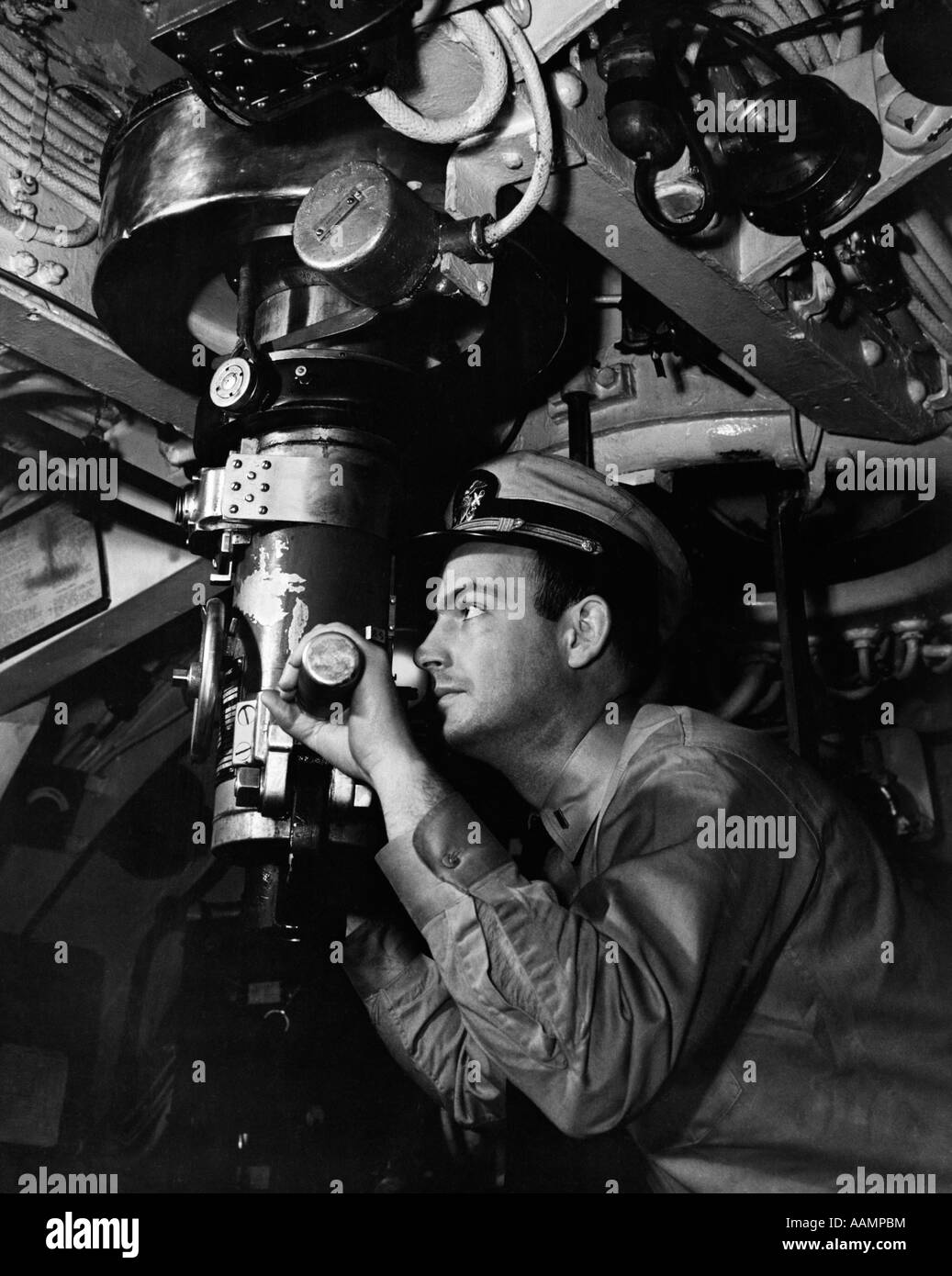 1940s SUBMARINE OFFICER CAPTAIN LOOKING THROUGH PERISCOPE OBSERVE UNDERWATER NAVAL UNIFORM WW2 VISION OBSERVATION VINTAGE Stock Photo