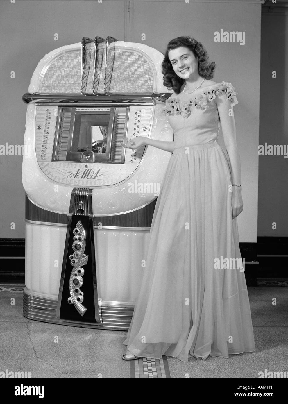 1940s PORTRAIT OF WOMAN IN BALL GOWN IN FRONT OF JUKEBOX Stock Photo