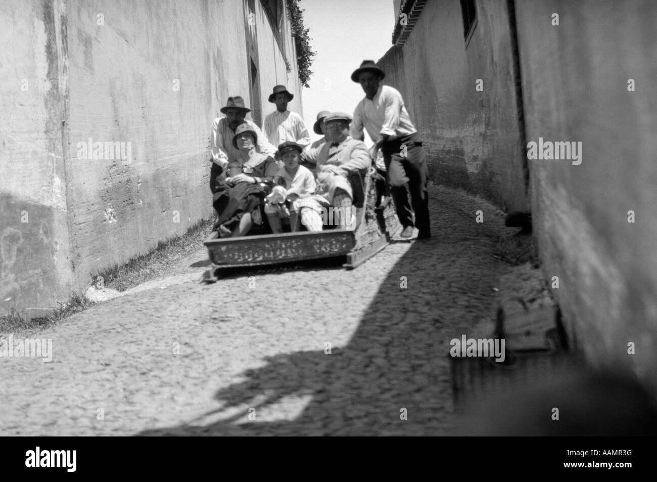 1920s 1930s MADEIRA ISLANDS TOURISTS SLIDING SLIDE DOWN HILL IN A FUNICULAR STEERED BY LOCAL GUIDES Stock Photo