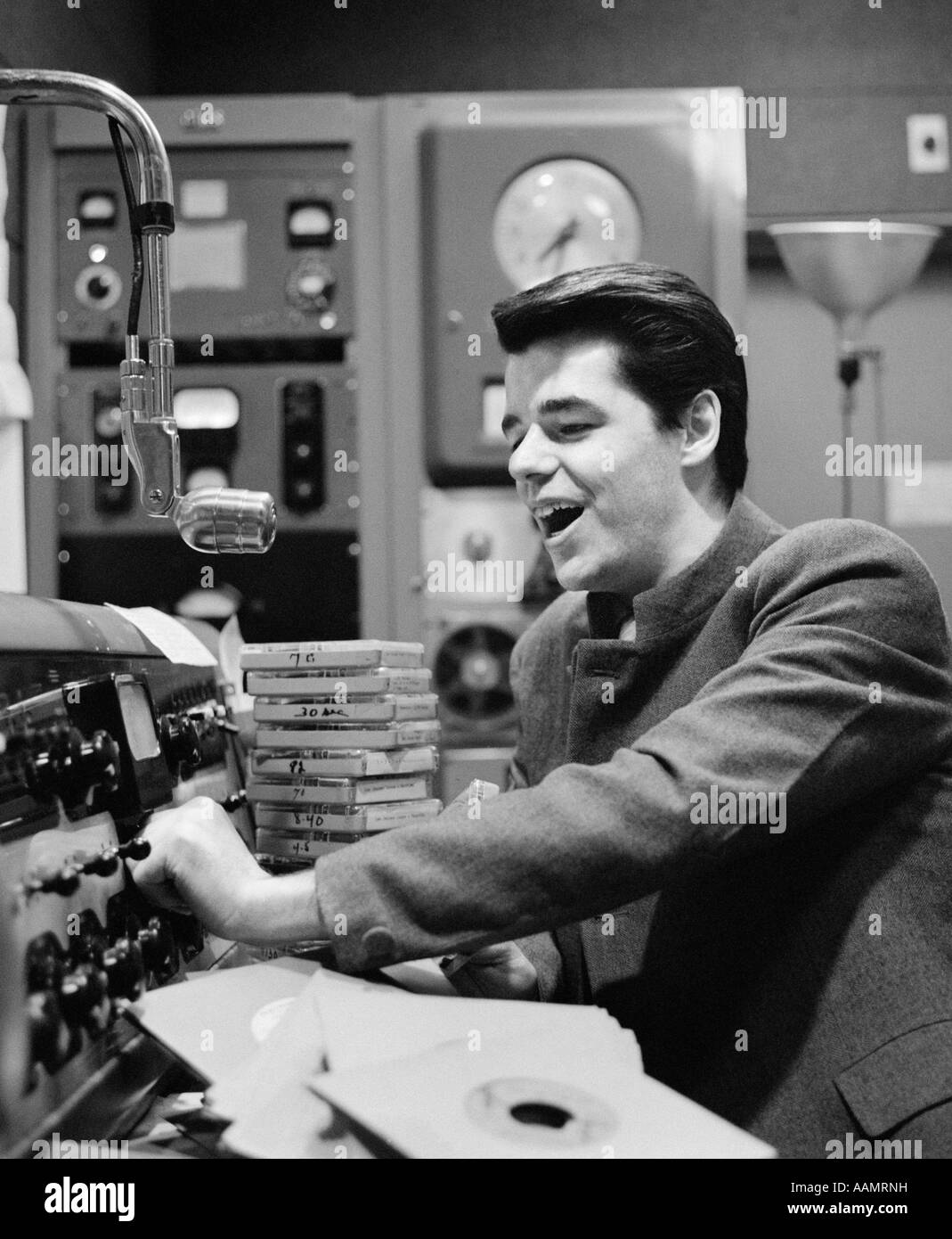1960s SIDE VIEW OF RADIO DISC JOCKEY IN STUDIO ANNOUNCING Stock Photo
