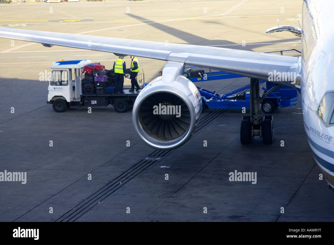baggage handlers and baggage vehicle behind wing of privilege hola airlines boeing 757 256 plane sitting on stand at dublin Stock Photo