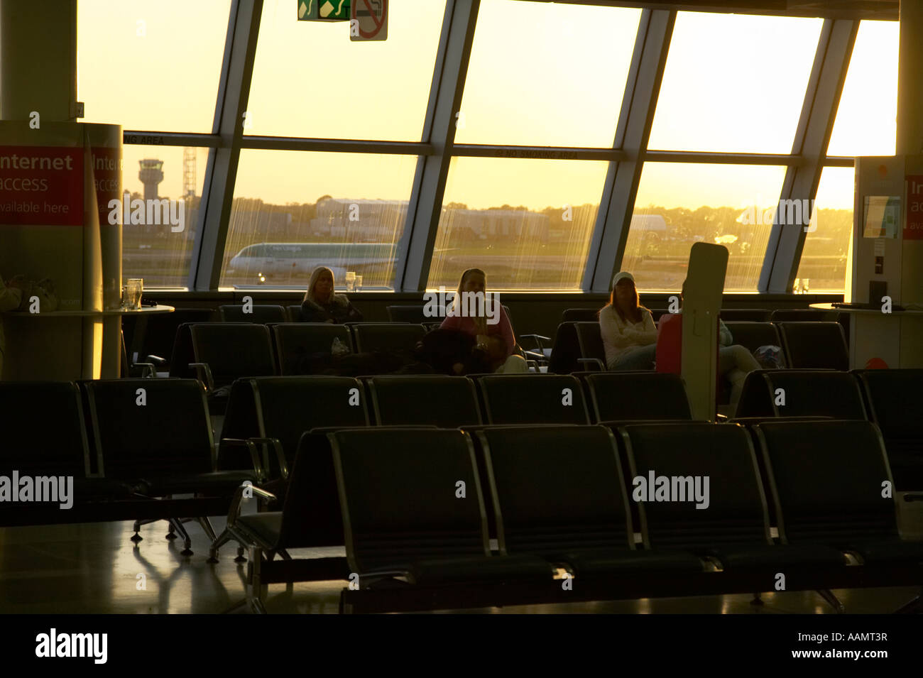 few remaining passengers sitting in no smoking departure area of dublin international airport in evening light ireland Stock Photo