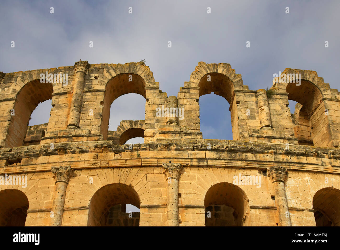 close up of the top of the old roman colloseum against blue cloudy sky el jem tunisia Stock Photo