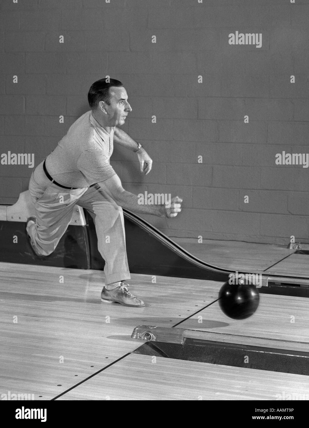 1950s MAN THROWING BOWLING BALL DOWN BOWLING ALLEY LANE Stock Photo