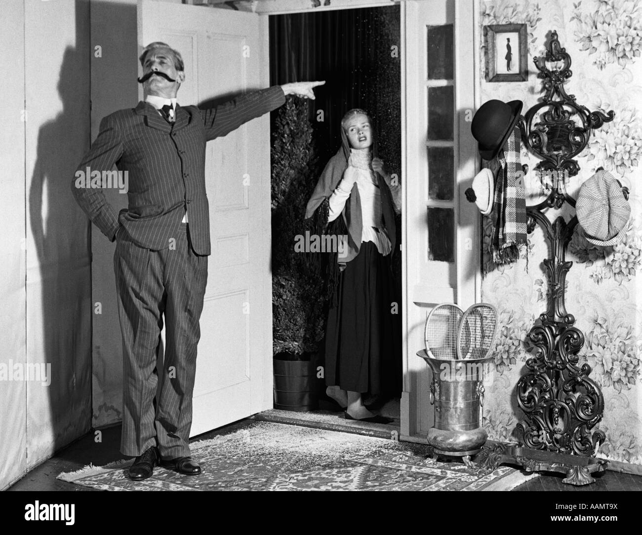 1960s SET-UP OF VICTORIAN MAN WITH HANDLEBAR MUSTACHE BANISHING WOMAN IN DOORWAY Stock Photo