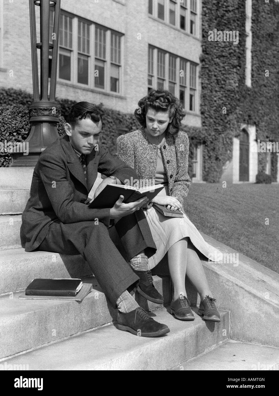 1940s 1930s MALE & FEMALE COLLEGE STUDENT STUDYING OUTSIDE ON CAMPUS STEPS Stock Photo