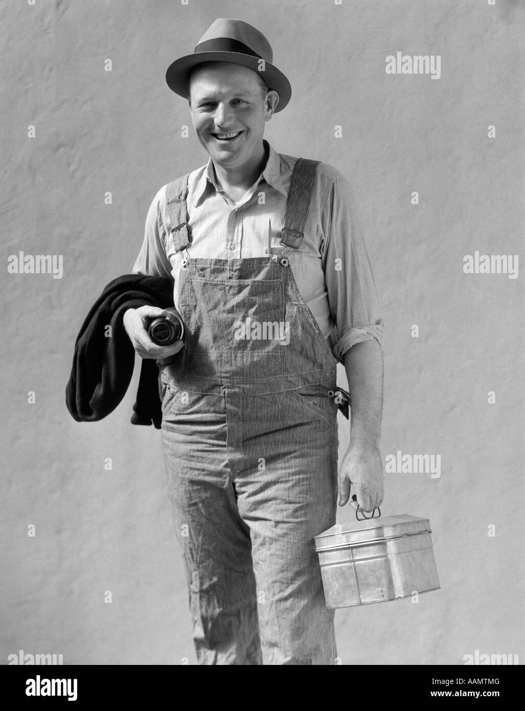 https://c8.alamy.com/comp/AAMTMG/1930s-smiling-man-in-work-clothes-overalls-holding-lunch-box-thermos-AAMTMG.jpg