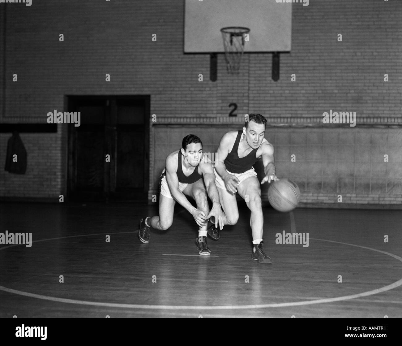 1930s TWO BOYS PLAYING BASKETBALL INSIDE COURT DRIBBLING BASKETBALL Stock Photo