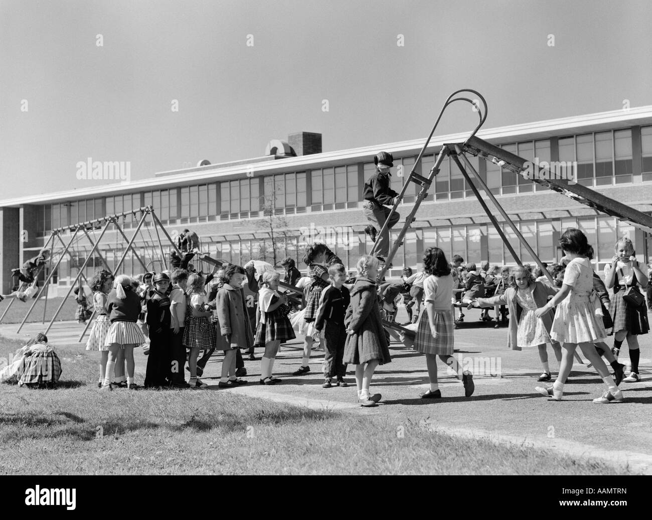 1950s ELEMENTARY SCHOOL PLAYGROUND AT RECESS WITH CHILDREN PLAYING ON