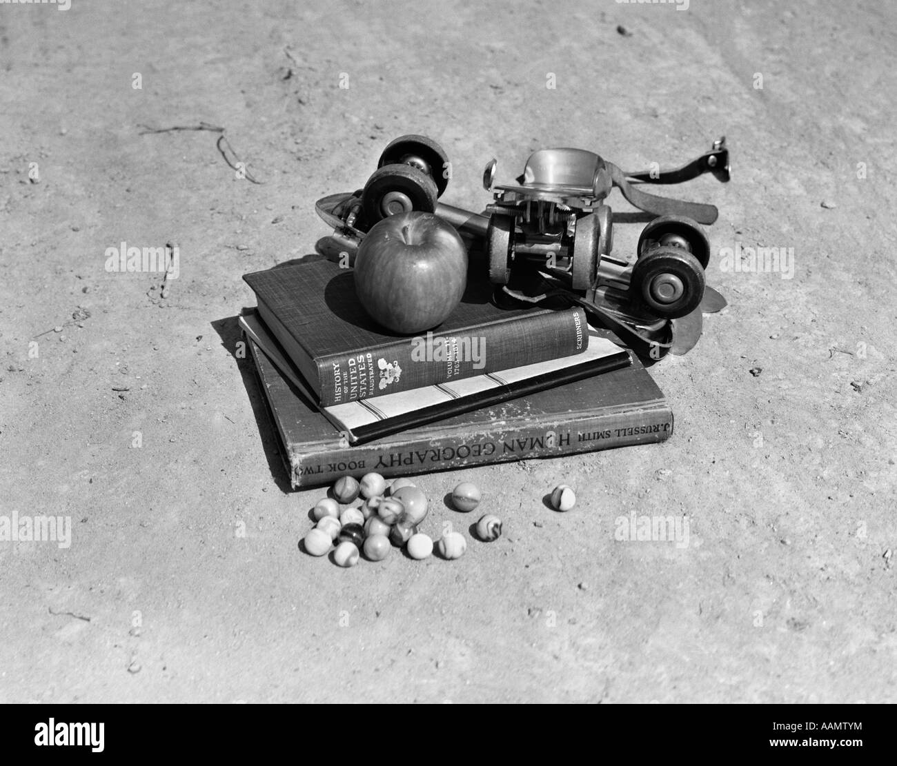 1930s 1940s STILL LIFE OF APPLE & PAIR OF ROLLER SKATES SITTING ON TOP OF PILE OF SCHOOL BOOKS Stock Photo