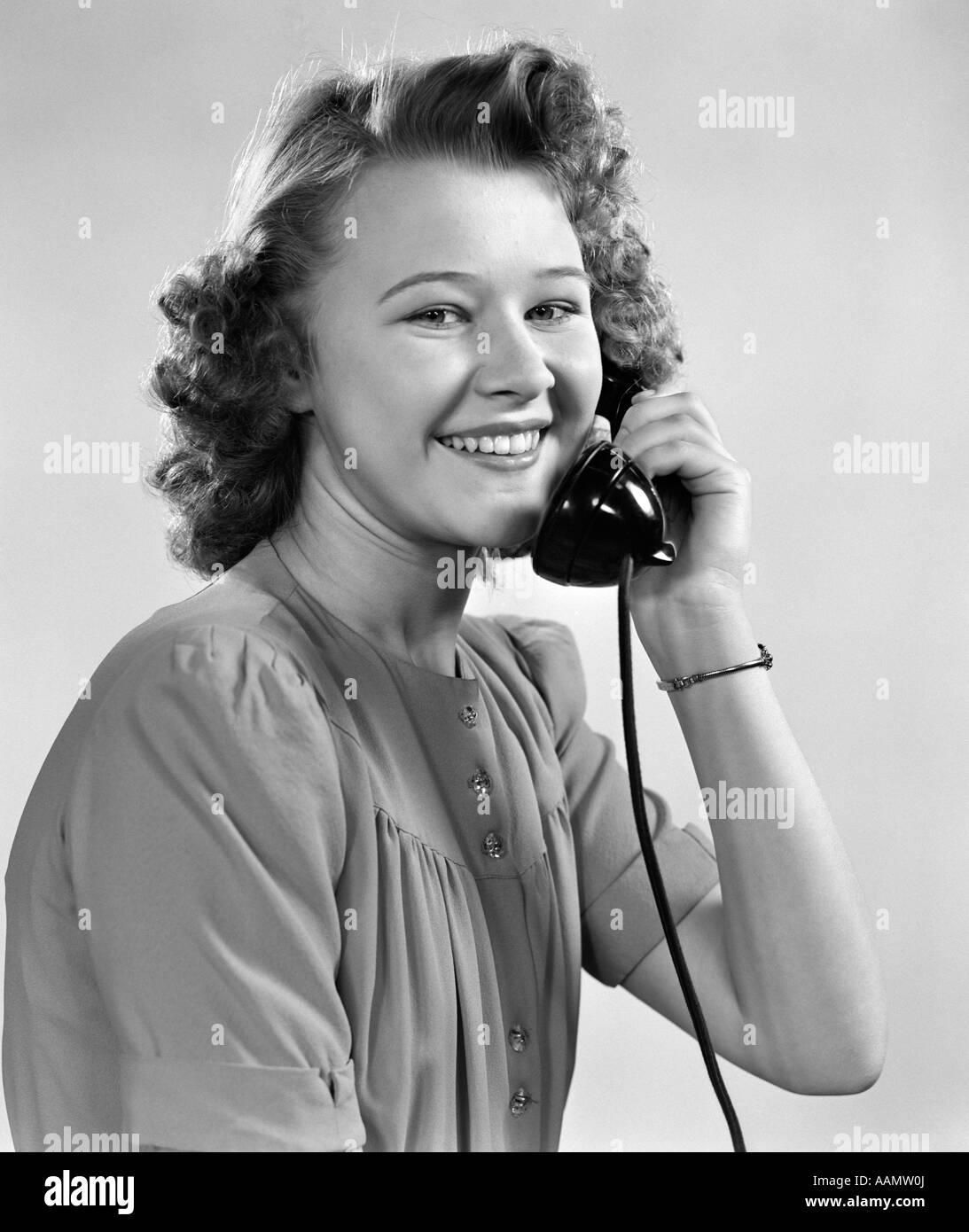 1940s YOUNG GIRL TALKING ON PHONE LOOKING AT CAMERA Stock Photo