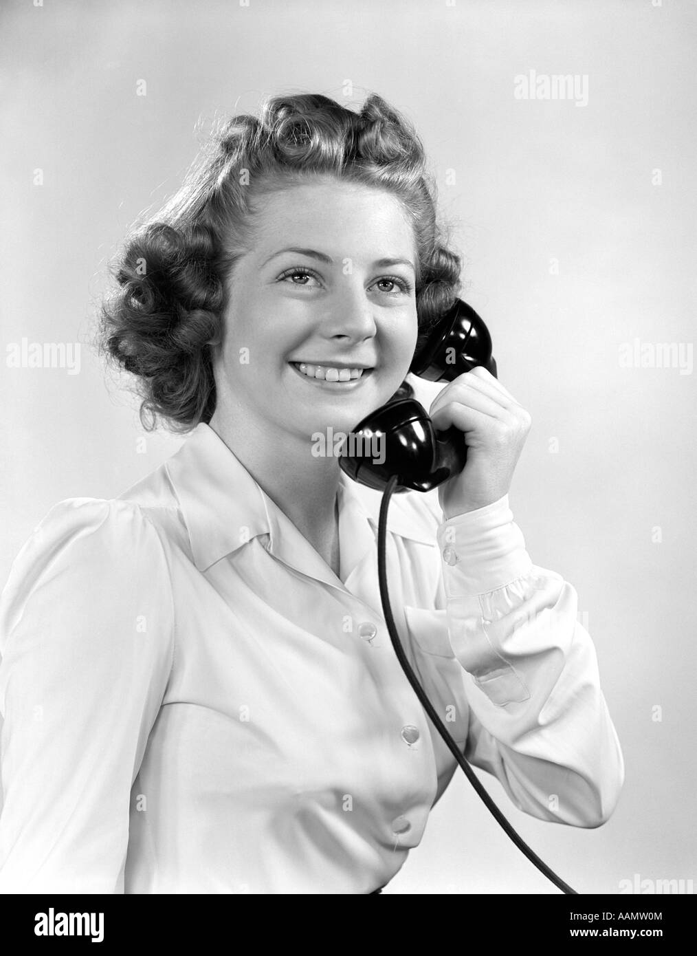 1940s YOUNG GIRL TALKING ON TELEPHONE SMILING WEARING WHITE BLOUSE Stock Photo