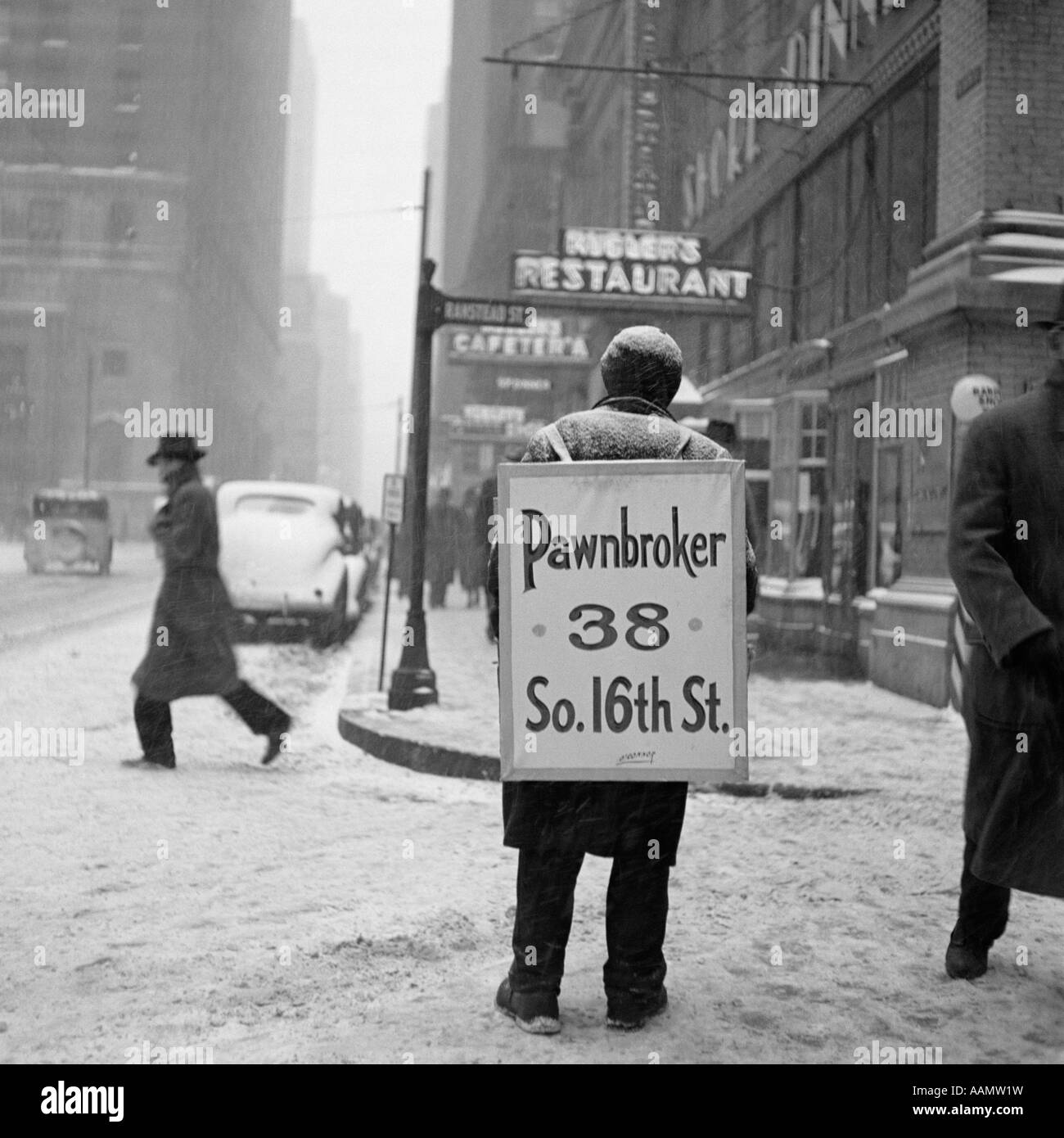 1930s WINTER STREET SCENE OF MAN WEARING PAWNBROKER SANDWICH BOARD Stock Photo
