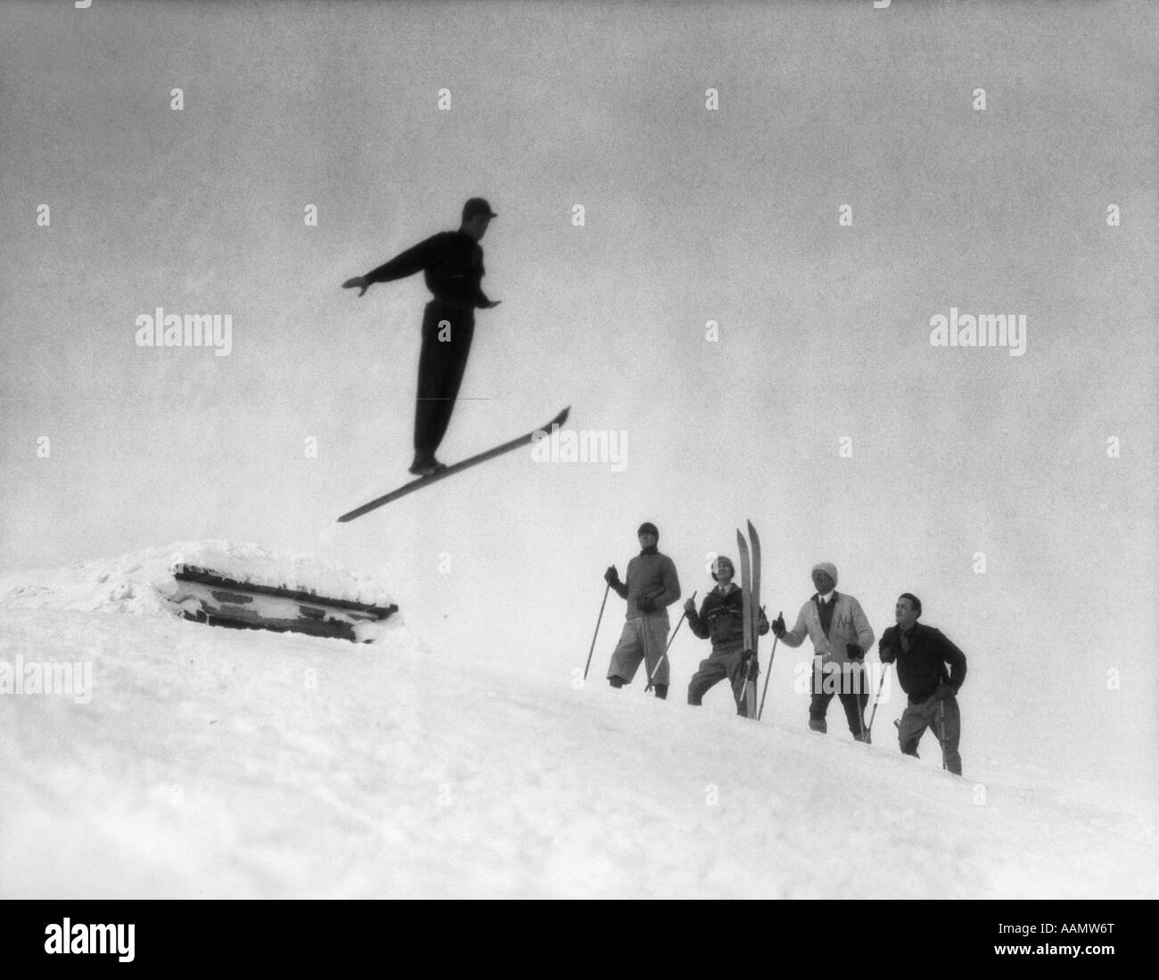 1920s MEN IN SNOW WEARING WOODEN SKIS WATCHING SKI JUMPER USING ONE ...