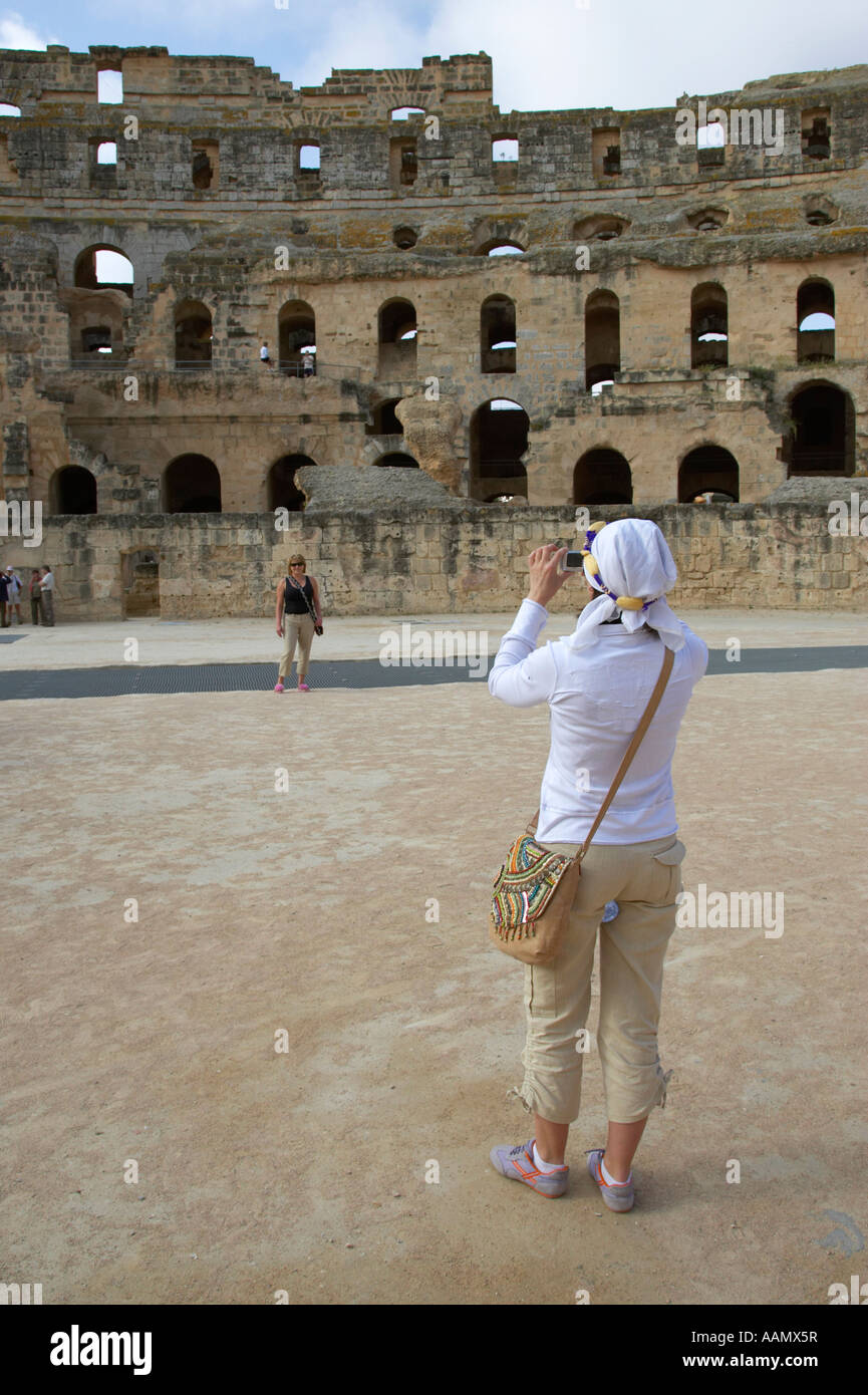 close up of two female tourists taking photo on the arena floor of the old roman colloseum at el jem tunisia vertical Stock Photo
