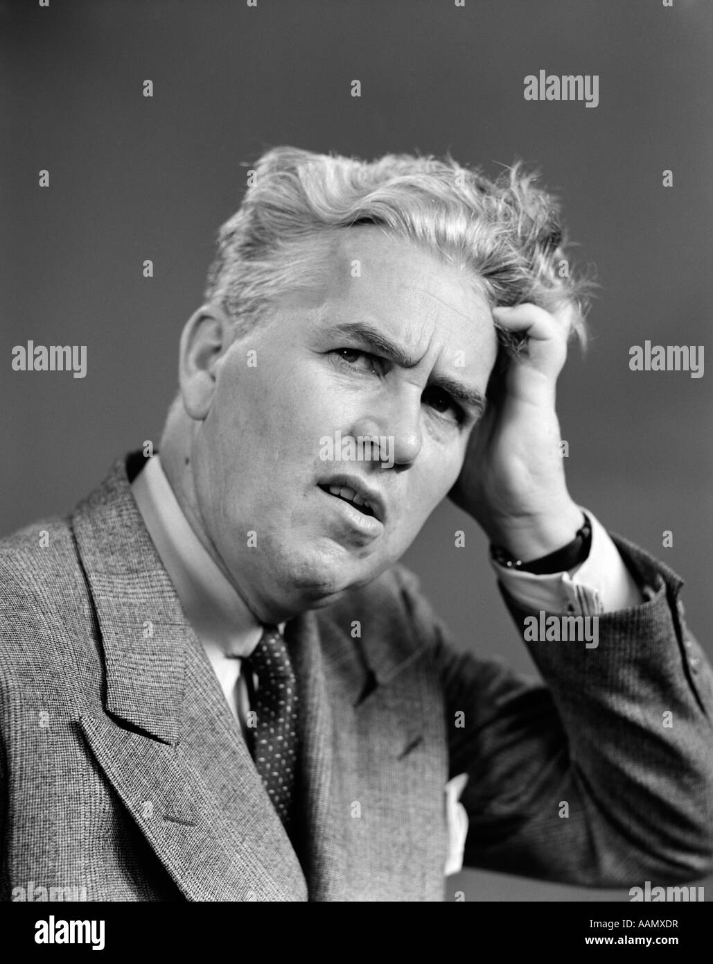 1930s 1940s MAN PORTRAIT HAND HELD UP TO HEAD FACIAL EXPRESSION FORGETFUL CONFUSED CONTEMPLATIVE SUIT TIE BUSINESS Stock Photo