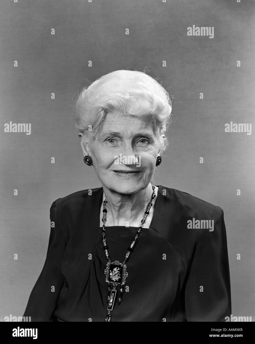 1950s PORTRAIT OF ELDERLY WHITE HAIRED WOMAN WITH SQUARE NECKED BLACK DRESS AND ANTIQUE JEWELRY Stock Photo