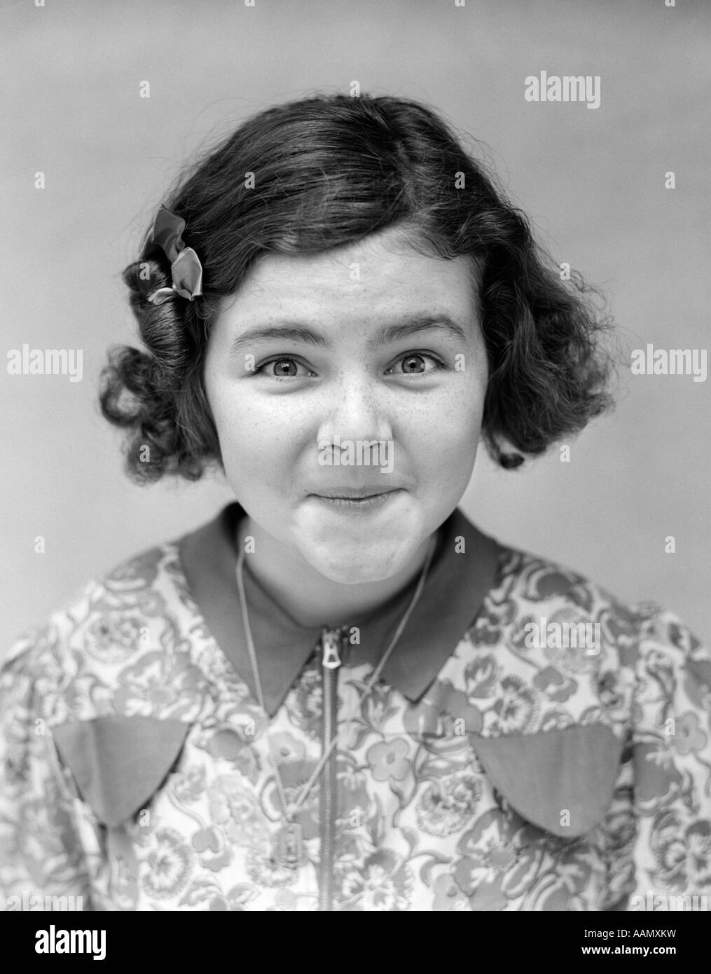 1930s PORTRAIT WIDE-EYED GIRL SMILING AT CAMERA LIPS MOUTH CLOSED Stock Photo