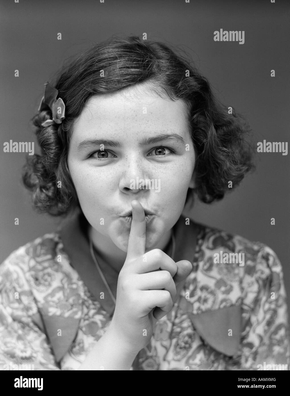 1930s PORTRAIT OF YOUNG GIRL WITH FINGER TO MOUTH MAKING SHUSH BE QUIET EXPRESSION Stock Photo