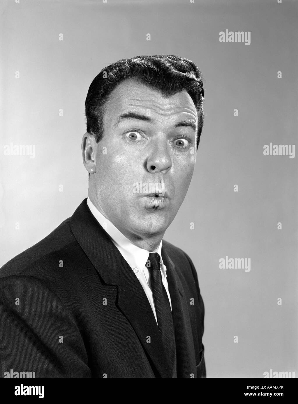 1960s MAN SUIT TIE MAKING FUNNY FACE FACIAL EXPRESSION LIPS PURSED EYES WIDE Stock Photo