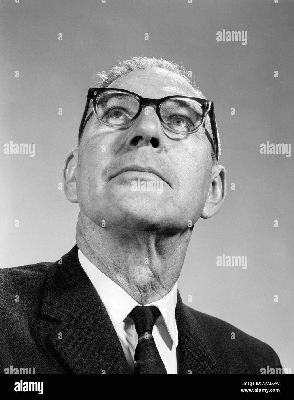1960s ELDERLY MAN WEARING EYE GLASSES LOOKING UP AT ODD ANGLE CHIN NECK SUIT TIE OPTICAL VISION Stock Photo