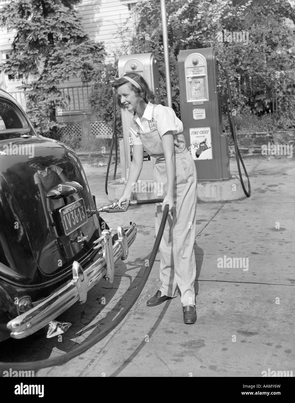 1940s WOMAN GAS STATION ATTENDANT FILLING CAR TANK Stock Photo