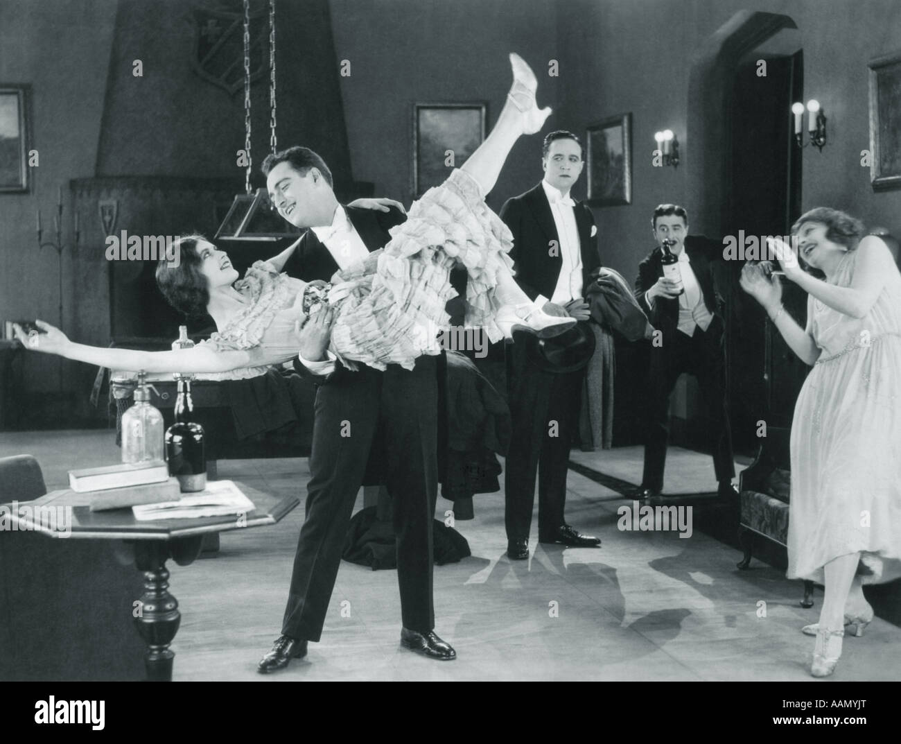 1920s MOVIE STILL OF WILD PARTY WITH WOMAN FLAPPER TURNED UPSIDE-DOWN IN ARMS OF MAN DANCING Stock Photo