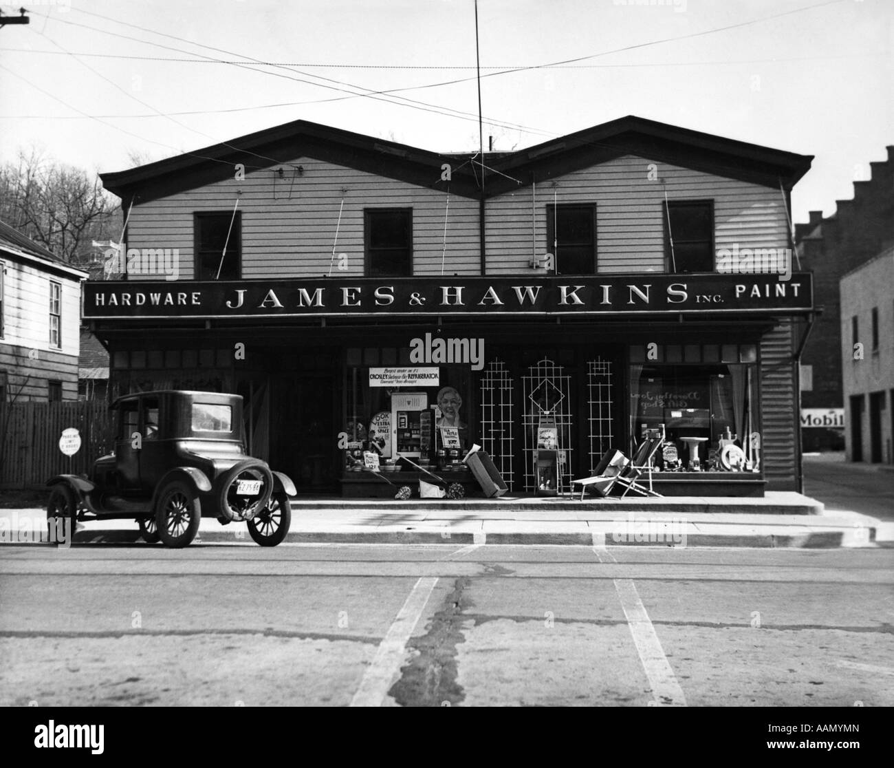 1920s FACADE OF HARDWARE STORE SINGLE CAR PARKED ON STREET IN FRONT