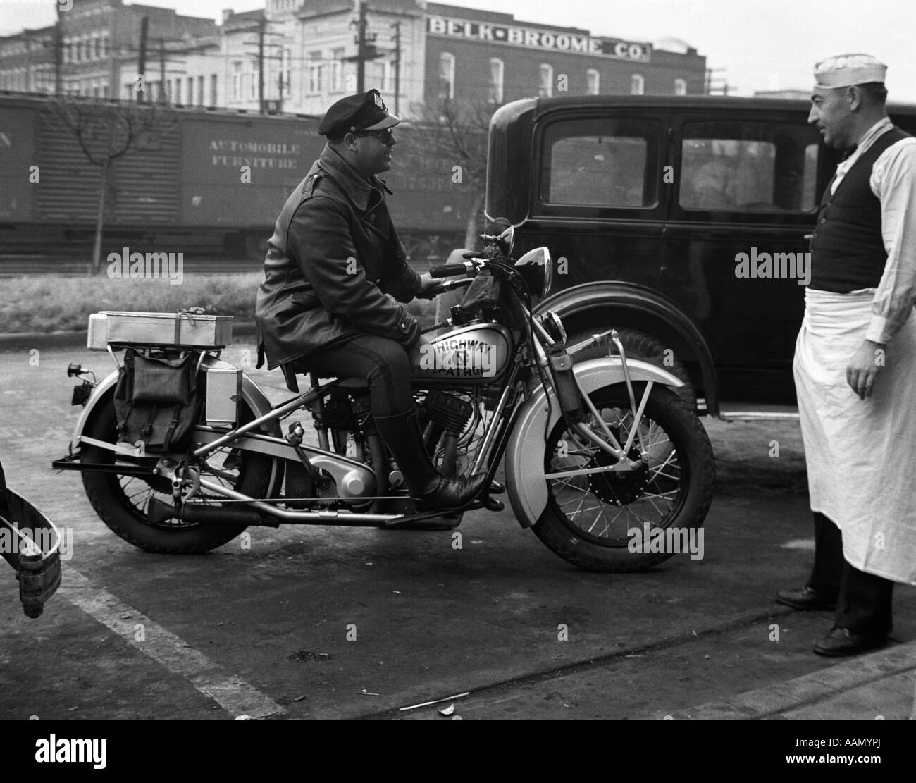 1930s NORTH CAROLINA MOTORCYCLE HIGHWAY PATROL POLICE OFFICERS PULL UP TO CURB TO TALK WITH LUNCH ROOM MAN Stock Photo