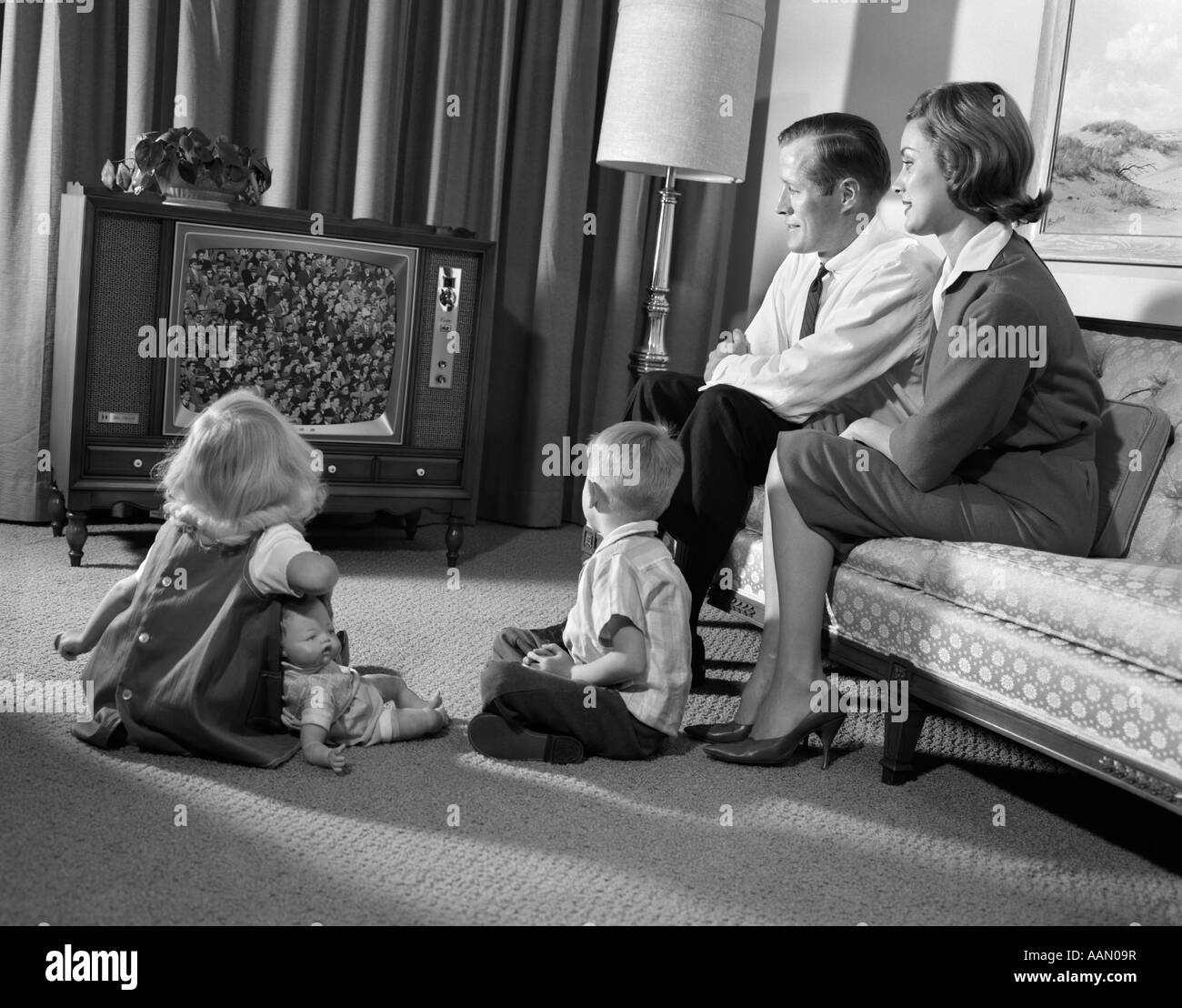 1960s FAMILY MOM DAD 2 KIDS WATCHING TELEVISION Stock Photo
